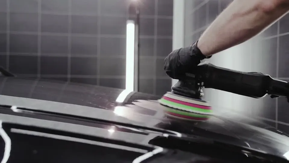Close-up of machine polishing on glossy black paintwork